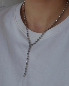 Detail of silver Y-shaped bead chain necklace worn on a simple white shirt