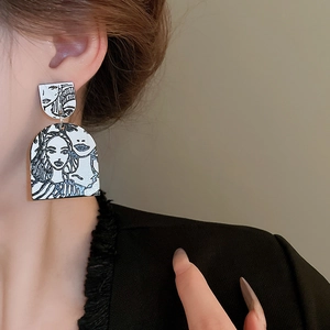 Close-up of minimalist black and white line art face earrings on a fashion model
