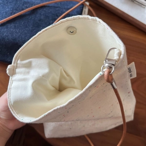 Detail of canvas bag showing interior lining, snap closure and metal swivel hooks