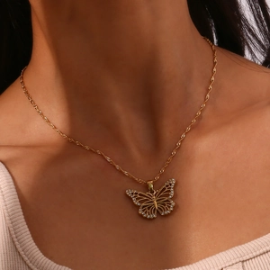 Close-up of golden hollow butterfly pendant with white rhinestones on model neck