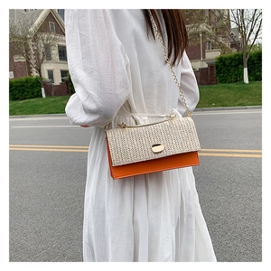 Détail du sac bandoulière en paille et cuir orange avec bandoulière chaîne dorée