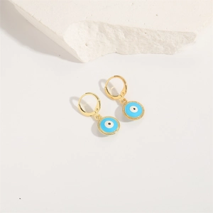 Minimalist evil eye gold dangle earrings with blue enamel on white stone background
