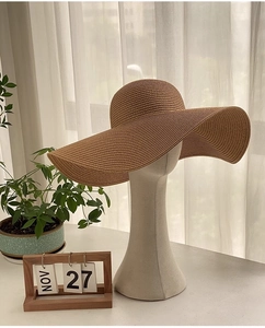 Détail du tissage fin en paille et du large bord d'un chapeau de soleil beige
