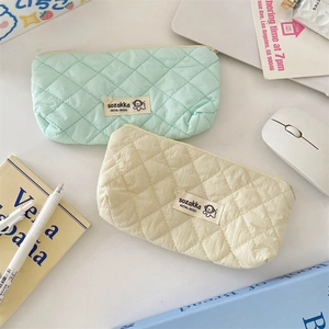 Detailed macro of macaron-colored quilted stationery bags in mint green and beige fabric