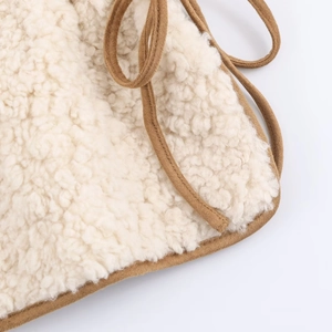 Detail of curly sherpa faux fur fabric texture with brown suede piping and fine stitching