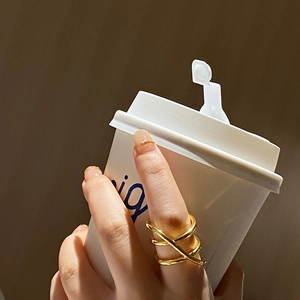 Minimalist gold-plated multilayer criss-cross ring shown in a lifestyle hand-holding scene
