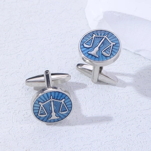 Macro shot of silver Libra scales cufflinks with blue enamel finish on stone surface