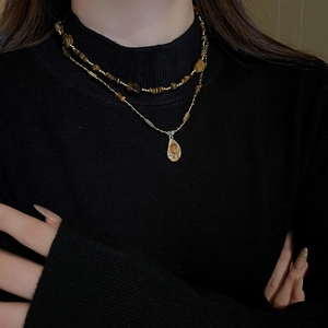 Détail d'un collier de perles marron à plusieurs rangs avec pendentif oeil de tigre irrégulier