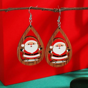 Macro view of teardrop wooden Christmas earrings with Santa Claus pattern on a branch