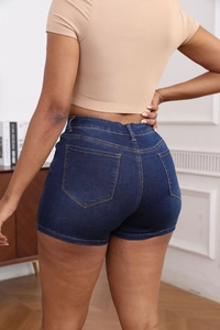 Detail view of high waist blue denim shorts with slim fit design and back pockets