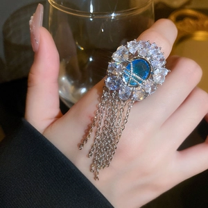 Detail of luxury gold plated ring with blue oval gemstone and sparkling zircon tassels