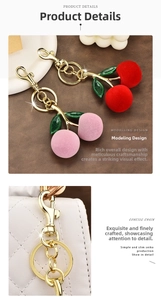 Detailed view of red and pink flocked cherry keychains with green leaves on leather