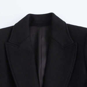 Detailed view of the notch lapel on a black wool blend coat with premium stitching