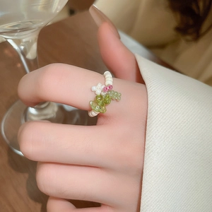 Detailed macro shot of elastic beaded flower ring with pink accents and green stone