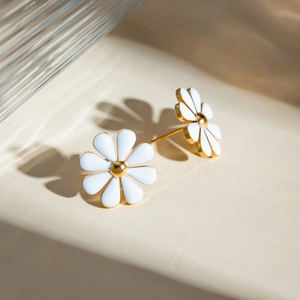 Macro detail of 18k gold plated daisy earrings with white enamel flower petals