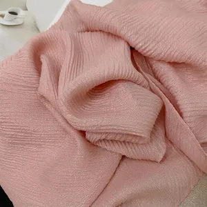 Dettaglio di una sciarpa plissettata rosa chiaro con lucentezza metallica e trama