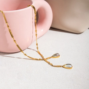 Detailed view of 18K gold stainless steel twisted chain with green teardrop pendants