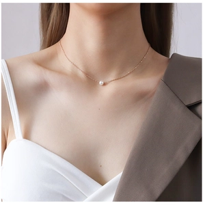 Close-up of elegant rose gold chain necklace with a small white pearl on model's neck