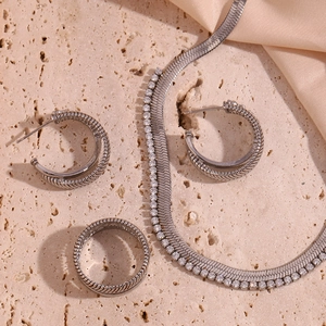 Macro detail of silver snake chain necklace and double layer earrings set on stone