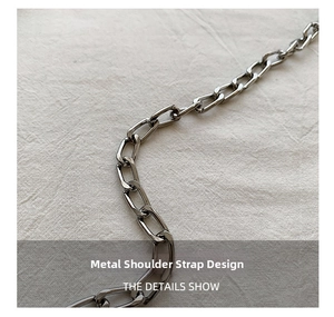 Macro shot of dark grey metal chain strap with rectangular links on textured fabric