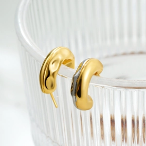 French style gold-plated C-shaped earrings with hammered texture on a glass rim