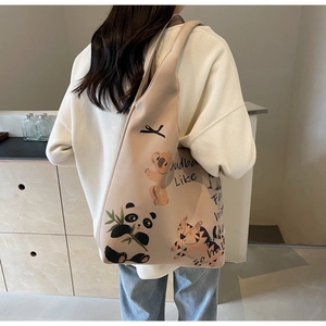 Beige canvas tote bag featuring cartoon animal illustrations worn on model's shoulder