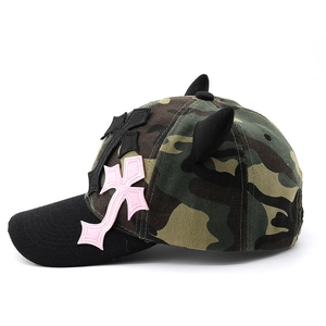Detail of pink cross patches and 3D devil horns on a camouflage baseball cap