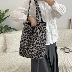 Detail of grey leopard print faux fur tote bag featuring a round gold metal logo