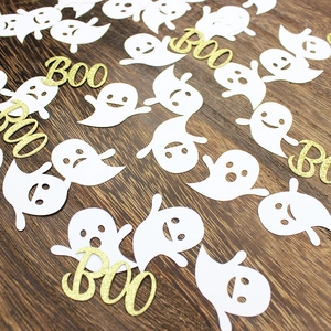 Halloween party confetti featuring white ghosts and golden glitter BOO letters on wood
