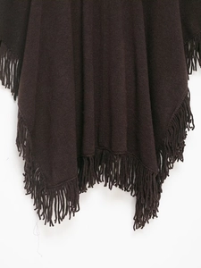 Detail of dark brown knitted poncho showing fine texture and long fringe hem tassels