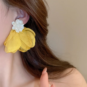 Close-up of a model wearing elegant yellow organza flower earrings with pearl accents