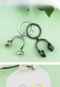 Close-up of stylish silver and black headphone-shaped metal keychains on green background