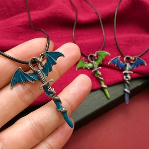 Detail shot of vintage dragon sword pendants with blue and green enamel and crystal inlay