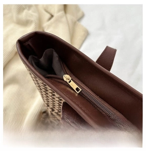 Detail view of golden metal zipper closure on houndstooth fabric and brown leather tote bag