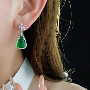 Close-up of a green gourd resin earring with sparkling zircon halo on a model ear