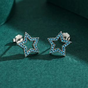 Boucles d'oreilles étoiles en argent 925 et turquoise sur fond vert foncé texturé