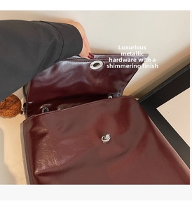 Detail view of glossy burgundy leather bag with silver twist lock and plush charm