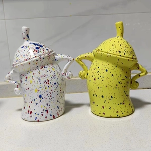 Detail of white and yellow spotted ceramic canisters with unique curved handle and lid