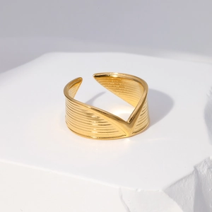 Macro shot of gold V-shaped open ring with horizontal striped texture on stone