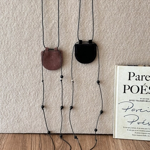 Detail of faux leather magnetic glasses holder necklace in black and brown minimalist style