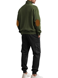 Dettaglio top in maglia verde con toppe sui gomiti e pantaloni cargo neri a quadri