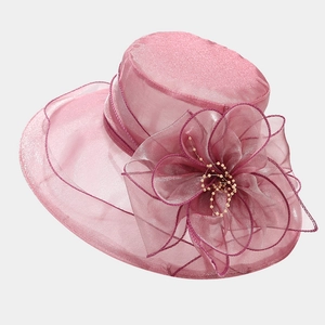 Détail d'un chapeau en organza rose avec une grande fleur faite main et perles dorées
