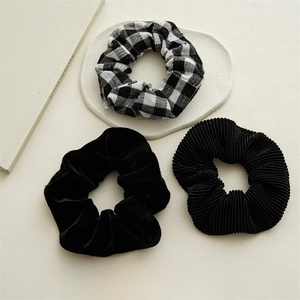 Detailed close-up of three black and checkered scrunchies on a minimalist stone tray
