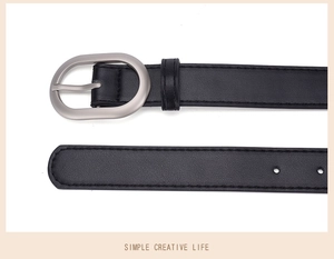 Detail view of a slim black PU leather belt with a matte silver oval buckle and pin