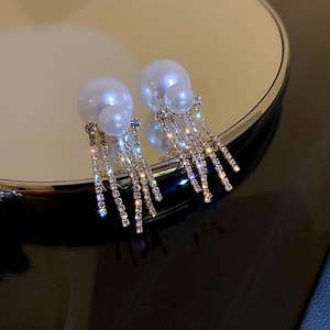 Elegant gold pearl tassel earrings with shimmering rhinestones on a mirror surface