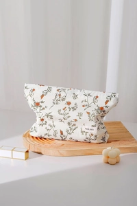 Dettaglio della borsa per cosmetici in cotone floreale su un vassoio di legno decorativo