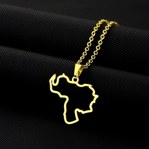 Detail of gold Venezuela map pendant with O-chain on textured dark fabric background