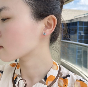 Close-up of a drop-shaped light blue zircon earring worn on ear with natural lighting