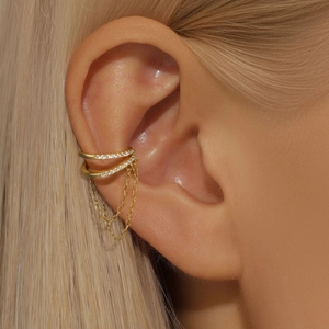 Close-up of golden double-layer ear cuff with sparkling zircon and long tassel chains