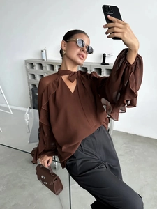 Detail of brown chiffon blouse featuring cascading ruffle sleeves and elegant V-neck tie strap